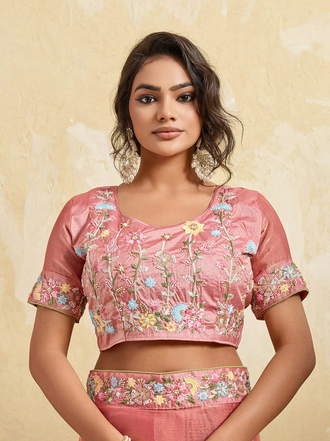 Woman wearing a pink embroidered blouse with a beige background